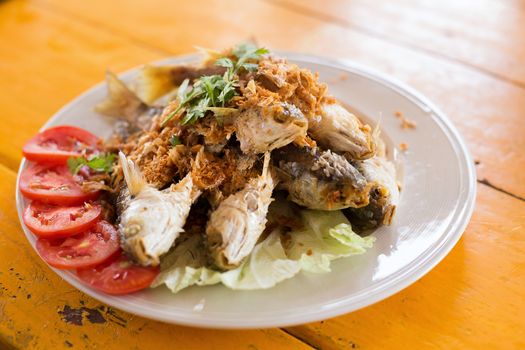 Fried fish with garlic on white plate.