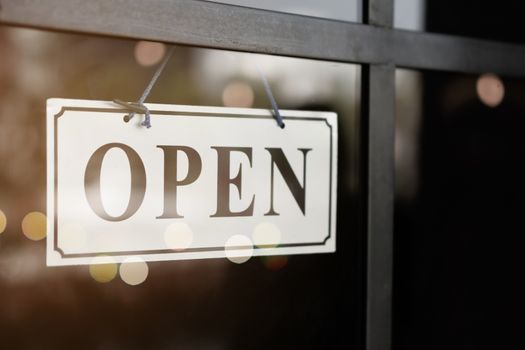 A business sign that says open on cafe or restaurant hang on door at entrance. Vintage color tone style.