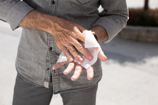 Old man cleaning hands with wet wipes, white