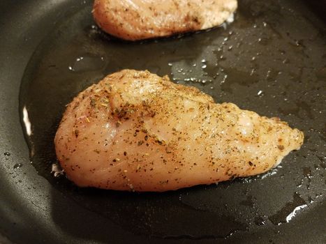 seasoned chicken breast or poultry in pan or skillet with oil