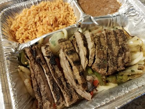 steak meat and rice and refried beans in foil tray or container