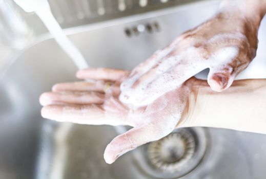 a young caucasian woman washing her hands with soap. Personal hygiene and virus prevention.