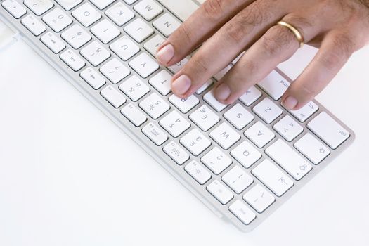 male hand typing on a white keyboard on a white table. White background.
