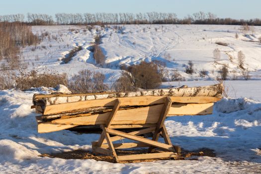 firewood lumber leftovers on trestle at winter evening with selective focus.
