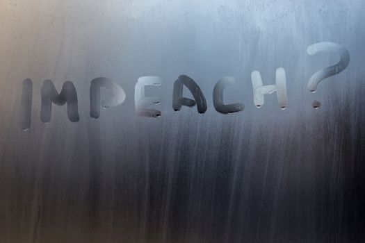 the question impeach written on wet window glass close-up with blurred background.