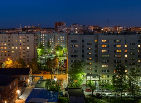 Windows, roofs and facade of an mass apartment buildings in Russia at at summer night