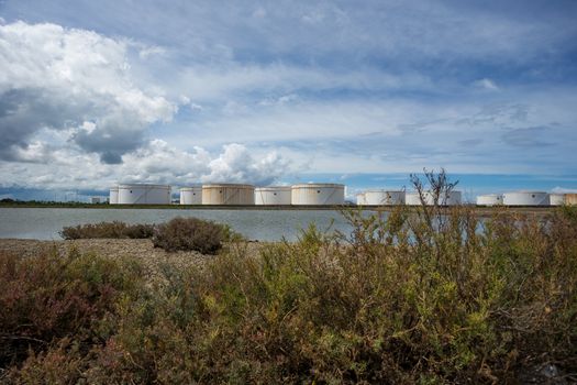 Oil tanks in a row under blue sky, Large white industrial tank for petrol, oil refinery plant. Energy and power.