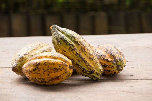 Raw Cocoa beans and cocoa pod on a wooden surface.