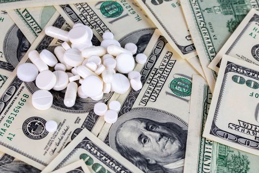 handful of white pills on dollar bills close-up with selective focus