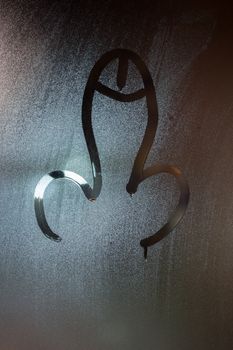 dick symbol drawed by finger on wet glass window at night - close-up with selective focus