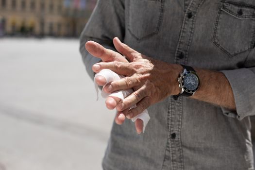 Old man cleaning hands with wet wipes, white