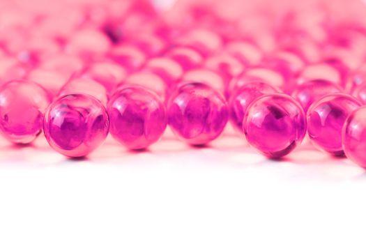 plastic pink spherical ball capsules with selective focus isolated on white background.