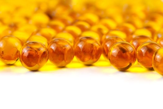 orange spherical ball capsules of fish oil selective focus isolated on white background.