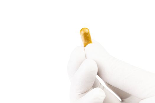 hand in medical glove holding organic med capsule isolated on white background closeup.
