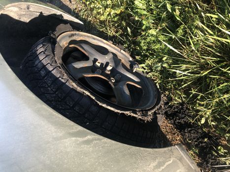 Destroyed blown out tire with exploded, shredded and damaged rubber on a modern suv automobile. Flat low profile tyre on an alloy rim, ripped open in pieces with visible interior. High quality photo