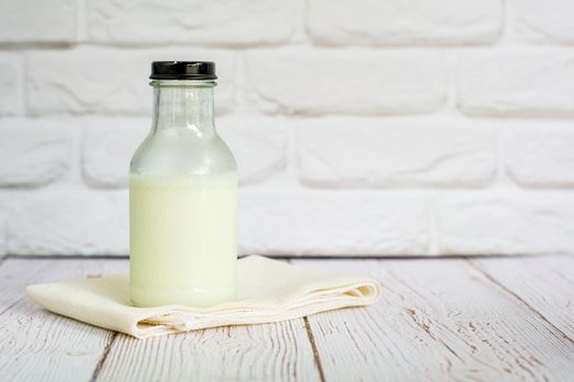 Bottle of fresh milk on white table cloth with wall in kitchen with copy space for your text. High calcium and vitamins. Good beverage for morning.