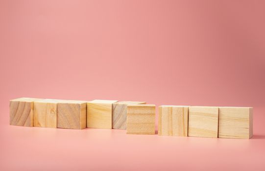 An empty wooden cube lined up on a pink background. For new ideas to be put into the picture.