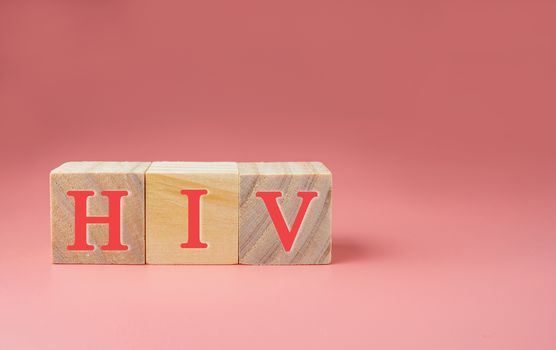 AIDS/HIV word on a wooden cube on pink background .Aids / HIV Concept.