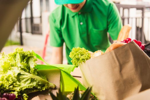 Asian delivery man grocery prepare service giving fresh vegetables food and fruit full in wooden basket on back car to send woman customer at door home after pandemic coronavirus, Back to new normal