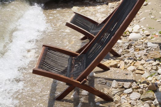 two empty wooden sun loungers on the seashore close up