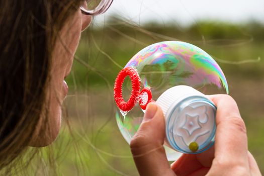 Close up photo of a girl blowing soap bubbles outdoor.
