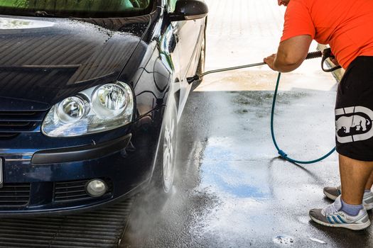 Washing and cleaning car in self service car wash station. Car washing using high pressure water in Bucharest, Romania, 2020