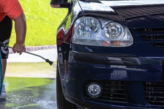 Washing and cleaning car in self service car wash station. Car washing using high pressure water in Bucharest, Romania, 2020