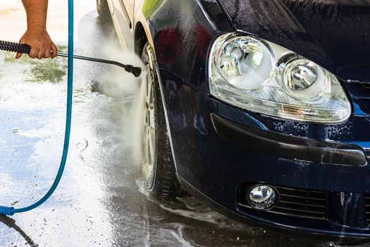 Washing and cleaning car in self service car wash station. Car washing using high pressure water in Bucharest, Romania, 2020