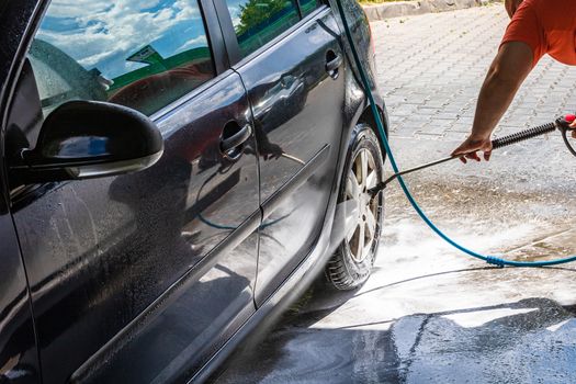 Washing and cleaning car in self service car wash station. Car washing using high pressure water in Bucharest, Romania, 2020