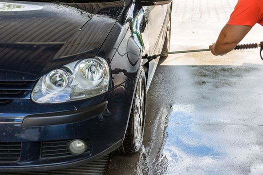 Washing and cleaning car in self service car wash station. Car washing using high pressure water in Bucharest, Romania, 2020