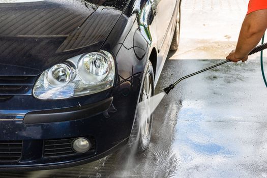 Washing and cleaning car in self service car wash station. Car washing using high pressure water in Bucharest, Romania, 2020