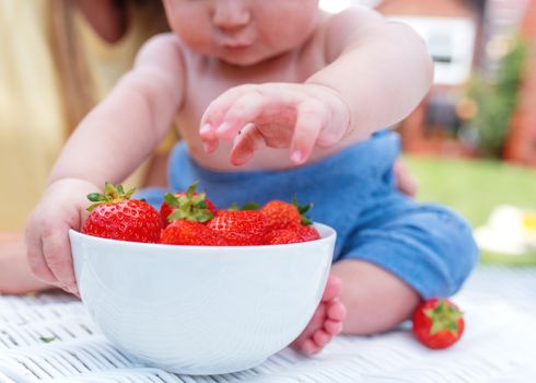 child grubbing strawberries in the bawl