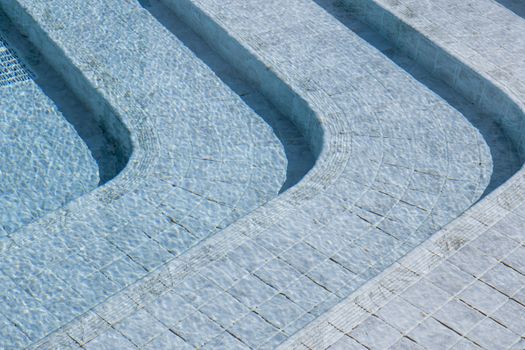 Curved steps at the swimming pool with blue tile mosaic