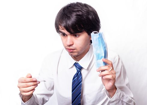 the young man with the mask looking at the thermometer in surprise