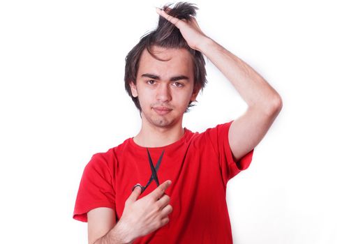 Young man in a red shirt with long hair and holding scissors on white background