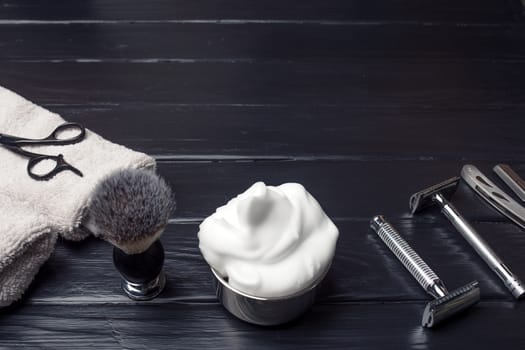 Razors, brush, towels and foam on a wood background.