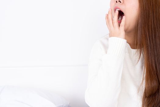 Asian woman are yawning covering open mouth with hand after she wake up. Healthcare medical or daily life concept.