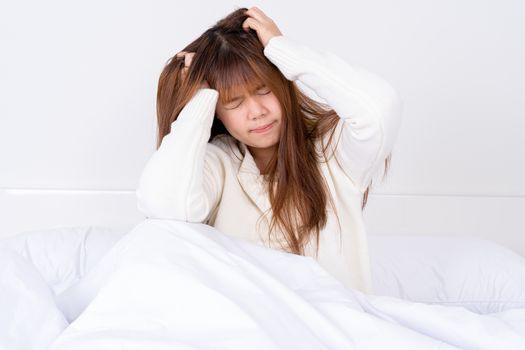 Young woman suffering from headaches after wake up on the bed. Healthcare medical or daily life concept.