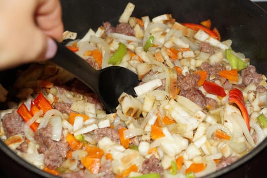 cooking vegetable stew with meat and sour cream in a saucepan