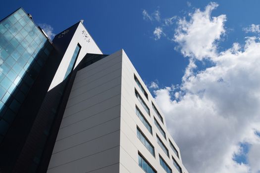 modern facade of a skyscraper against the backdrop of a sunny cloudy sky