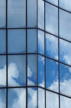 Clouds reflected in the glass facade of a skyscraper close up