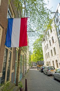 Old street in Amsterdam with the dutch flag on kingsday day