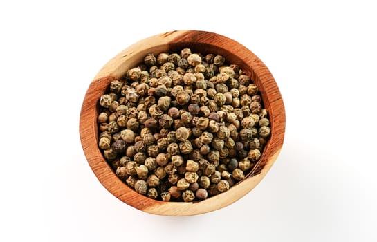 Dried white and green pepper corns in small wooden bowl - view form above isolated on white background.