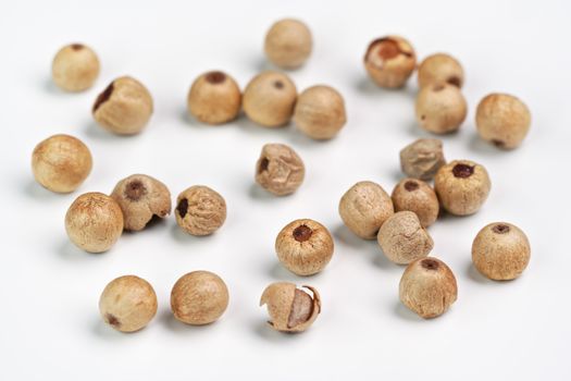 Dried white peppercorns isolated on white board, closeup detail.