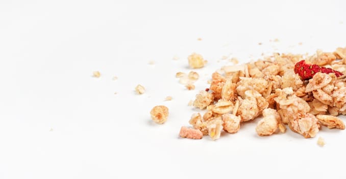 Muesli flakes with one dried strawberry, closeup photo isolated on white background space for text left side.