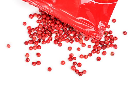 Pink peppercorns - dried fruits from peruvian peppertree Schinus molle , with red plastic pack near, closeup detail from above.