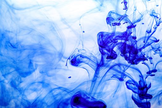 Blue ink injected into water from syringe, colour mixing with water creating abstract shapes.