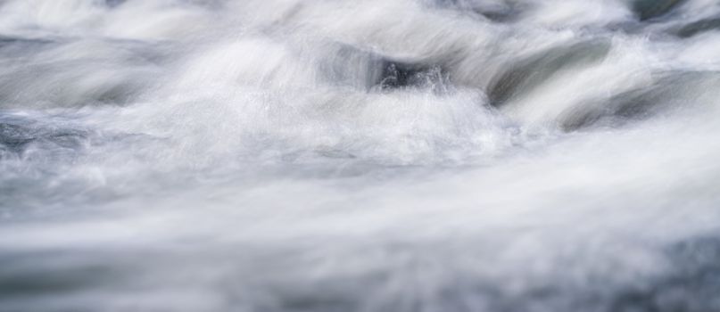 Long exposure photo - water flowing over rocks everything smooth, only few waterdrops in focus.