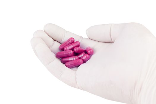 hand in medical glove holding plastic pink color organic med capsules isolated on white background closeup.