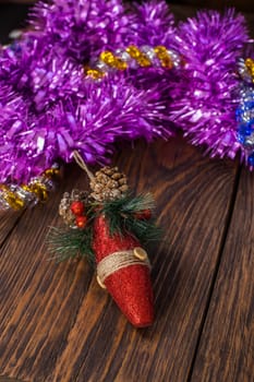 a christmas tree toy and purple tinsel on brown wood background - vertical orientation